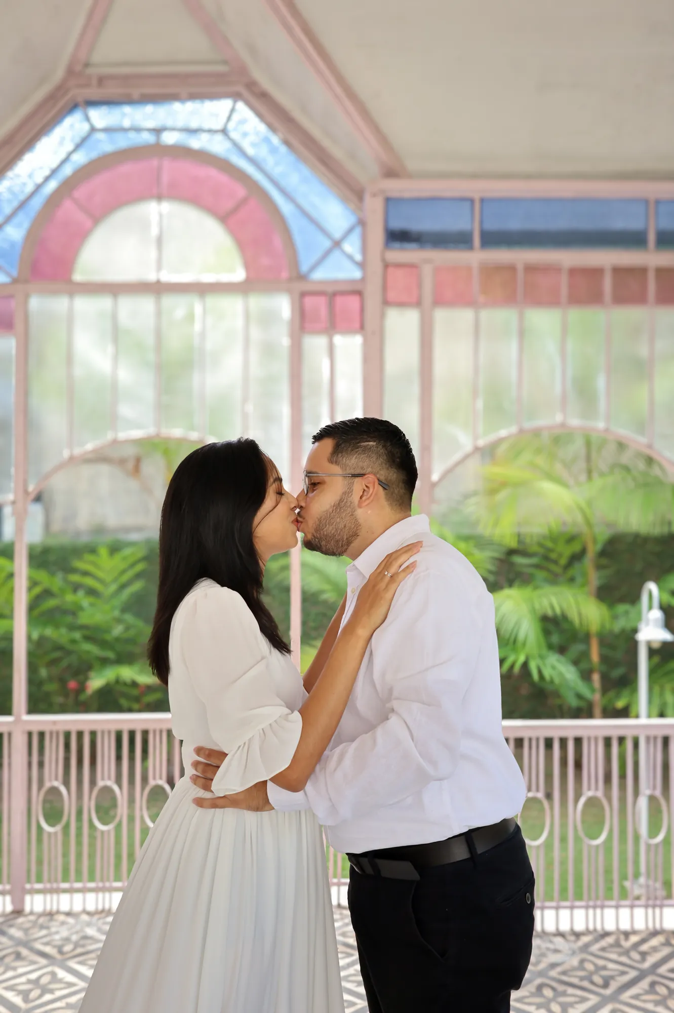 Casal se beijando dentro de um pavilhão de vidro rosa