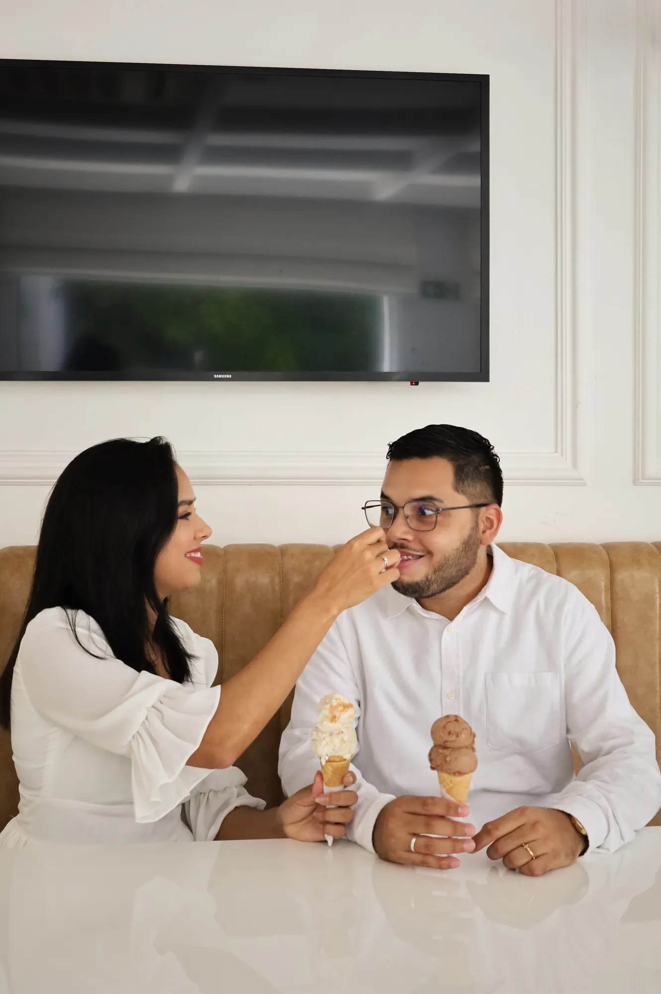 Casal dividindo sorvete em uma mesa de café, entre risadas