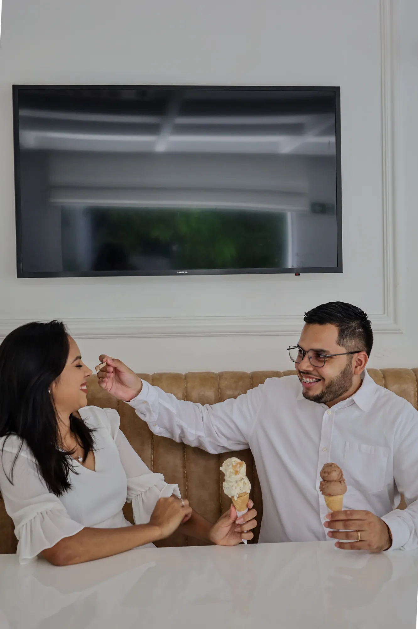 Casal brincando com casquinhas de sorvete em um café branco
