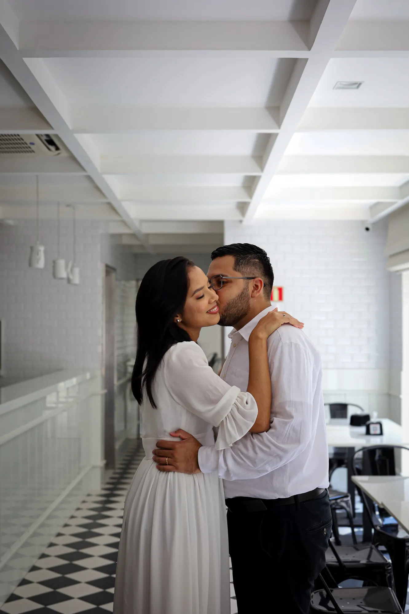 Casal se beijando em corredor de piso xadrez preto e branco